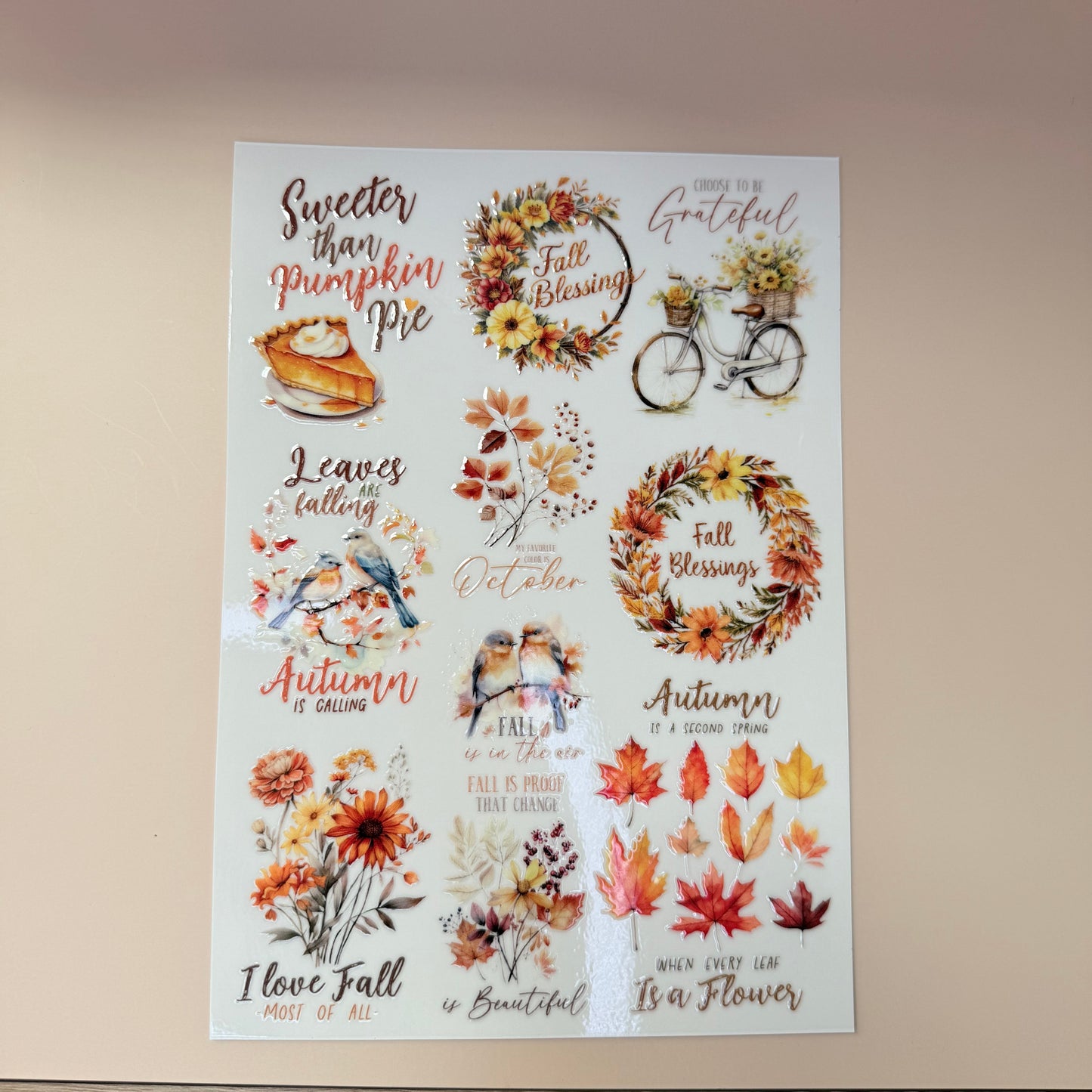 Sheet of autumn-themed stickers with leaves, wreaths, and text on a beige background