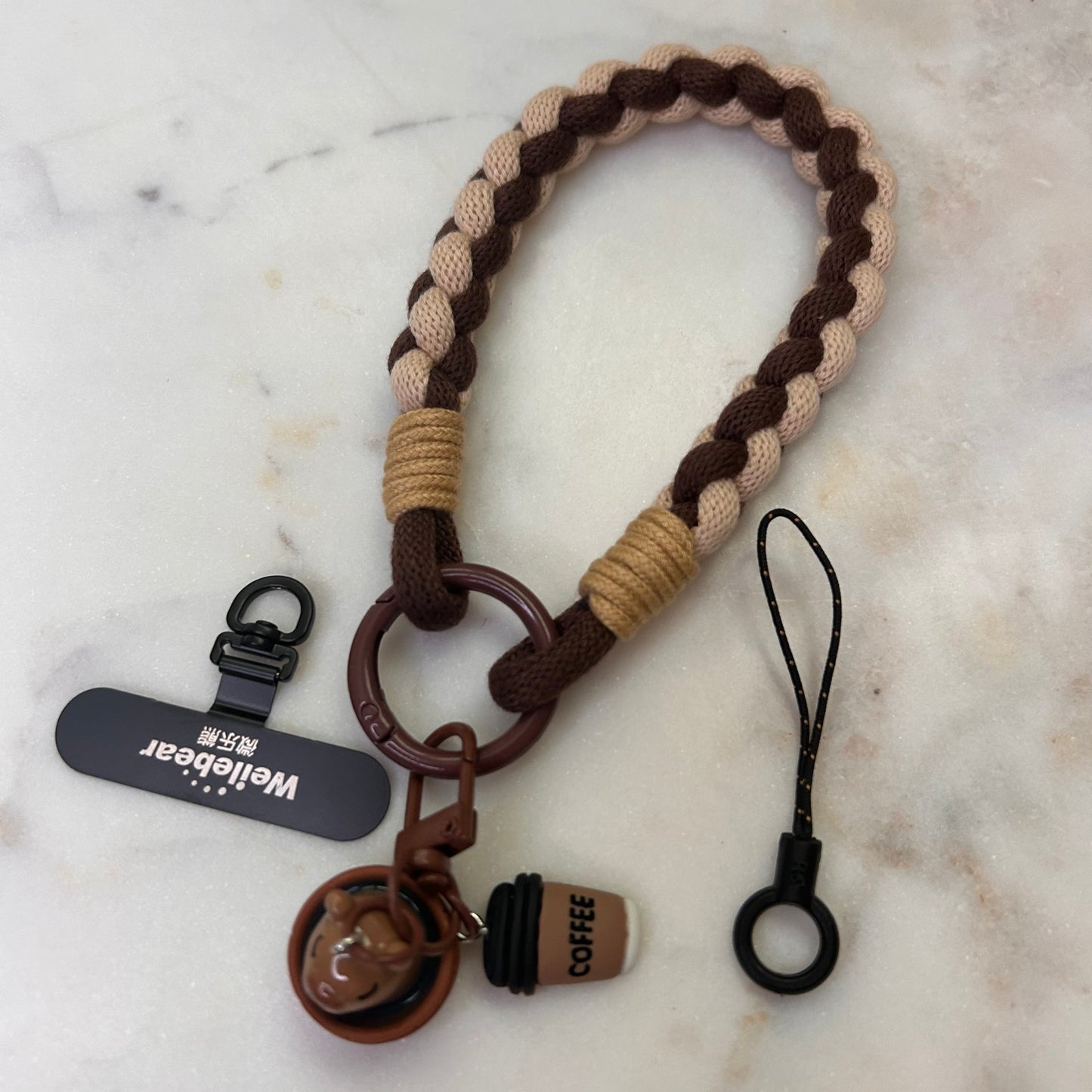 Keychain with braided design and attached tags on a marble surface