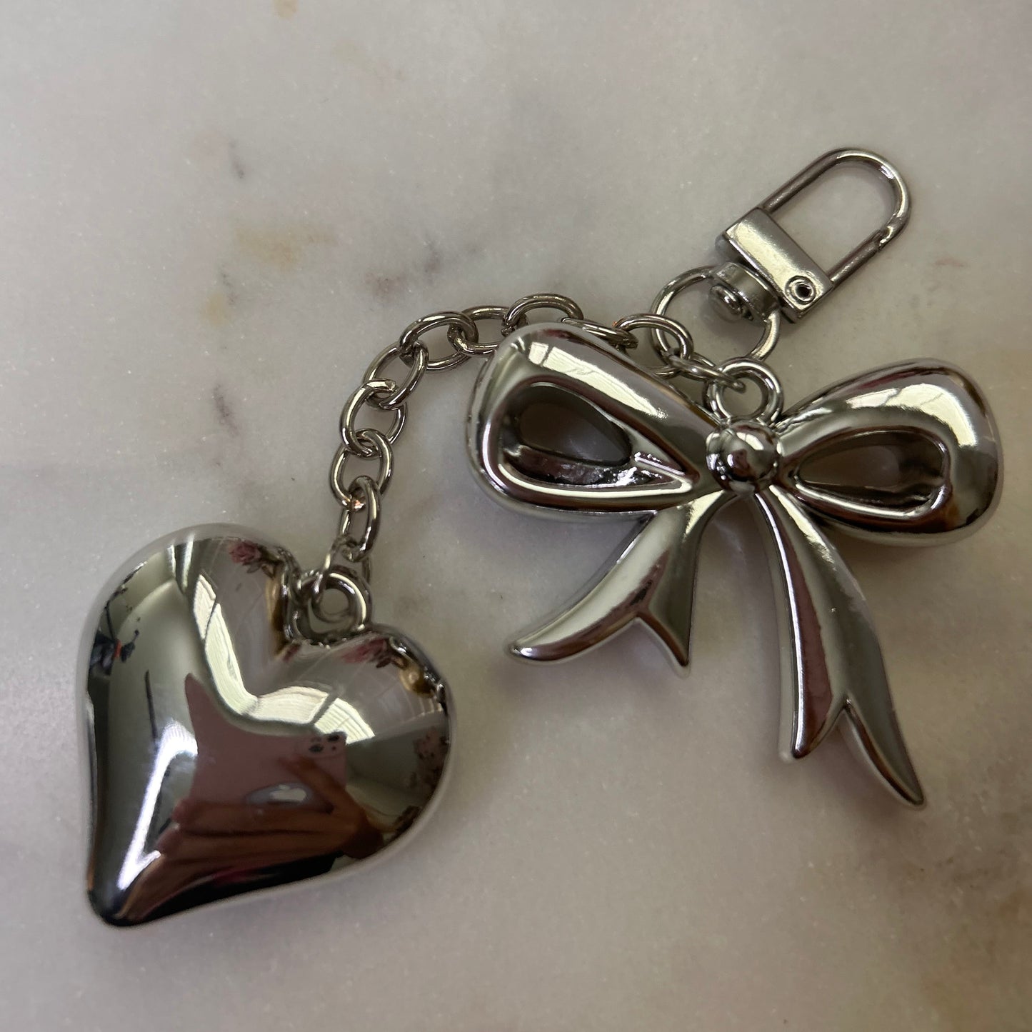 Silver angel and heart keychain on a marble surface