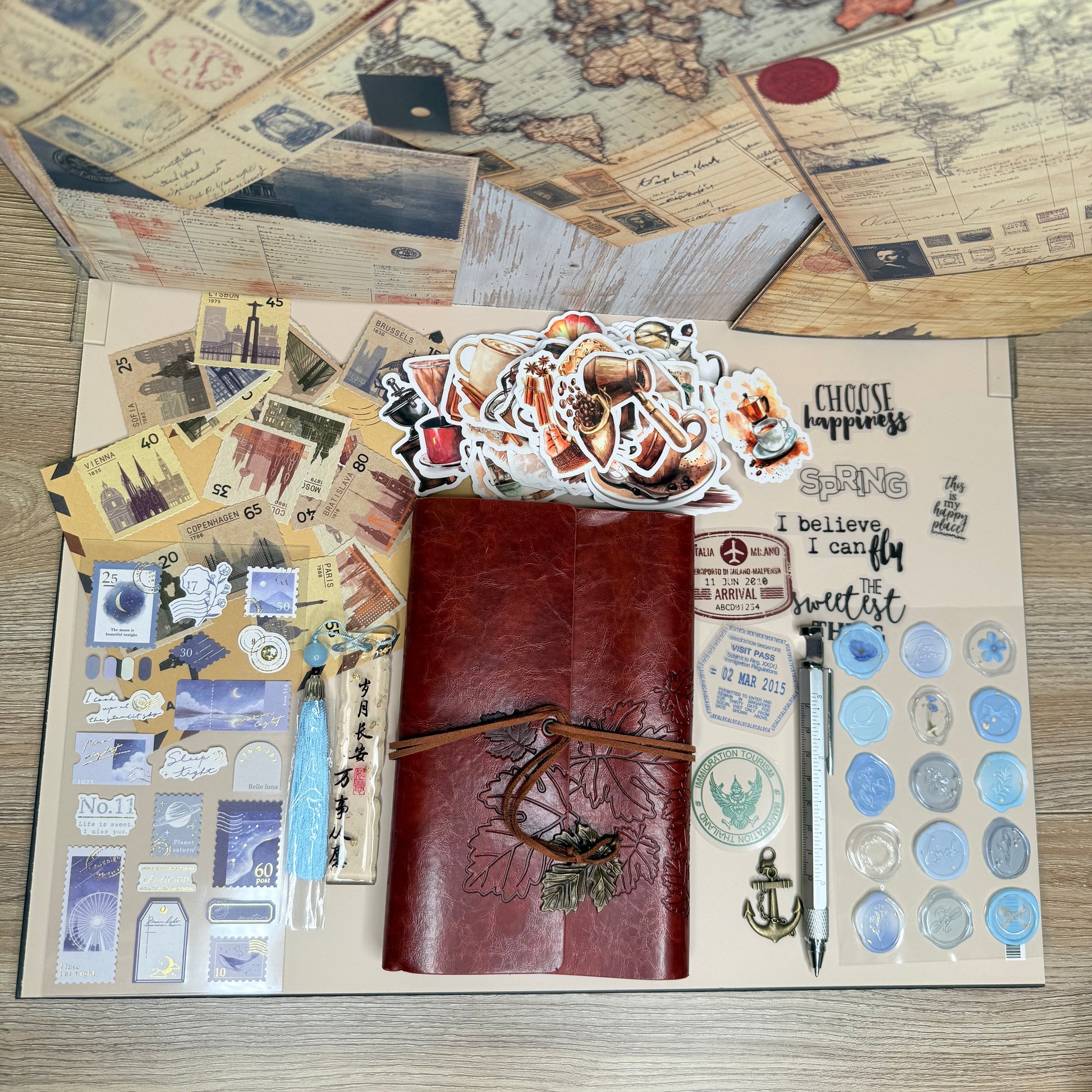 Collection of vintage-style items including a map, leather-bound books, and decorative stickers on a wooden surface.