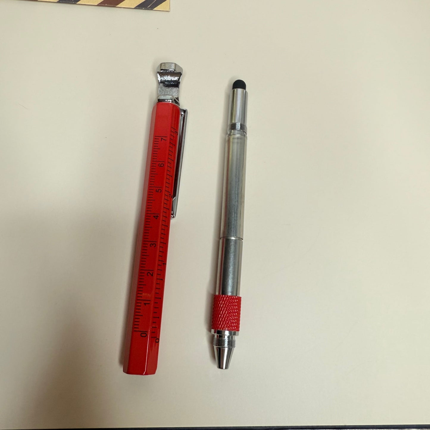 Pen and ruler on a light surface with decorative items around