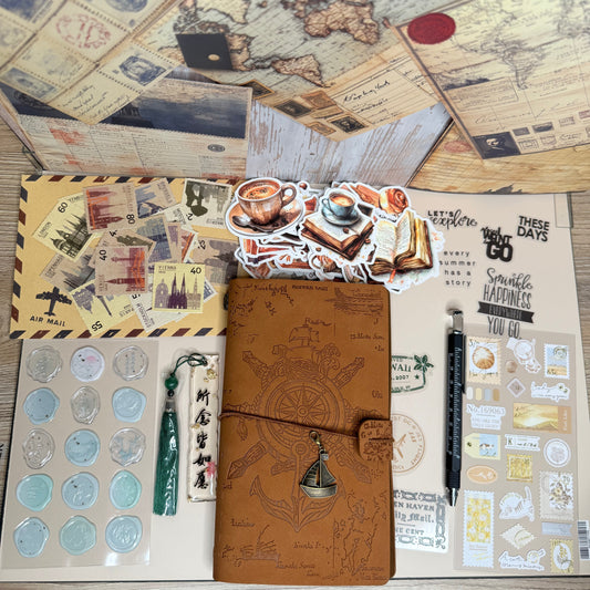 Collection of stationery items including a brown leather notebook, stickers, and a world map on a wooden surface.