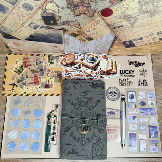 Collection of stationery items including a black notebook, stickers, and maps on a wooden surface.