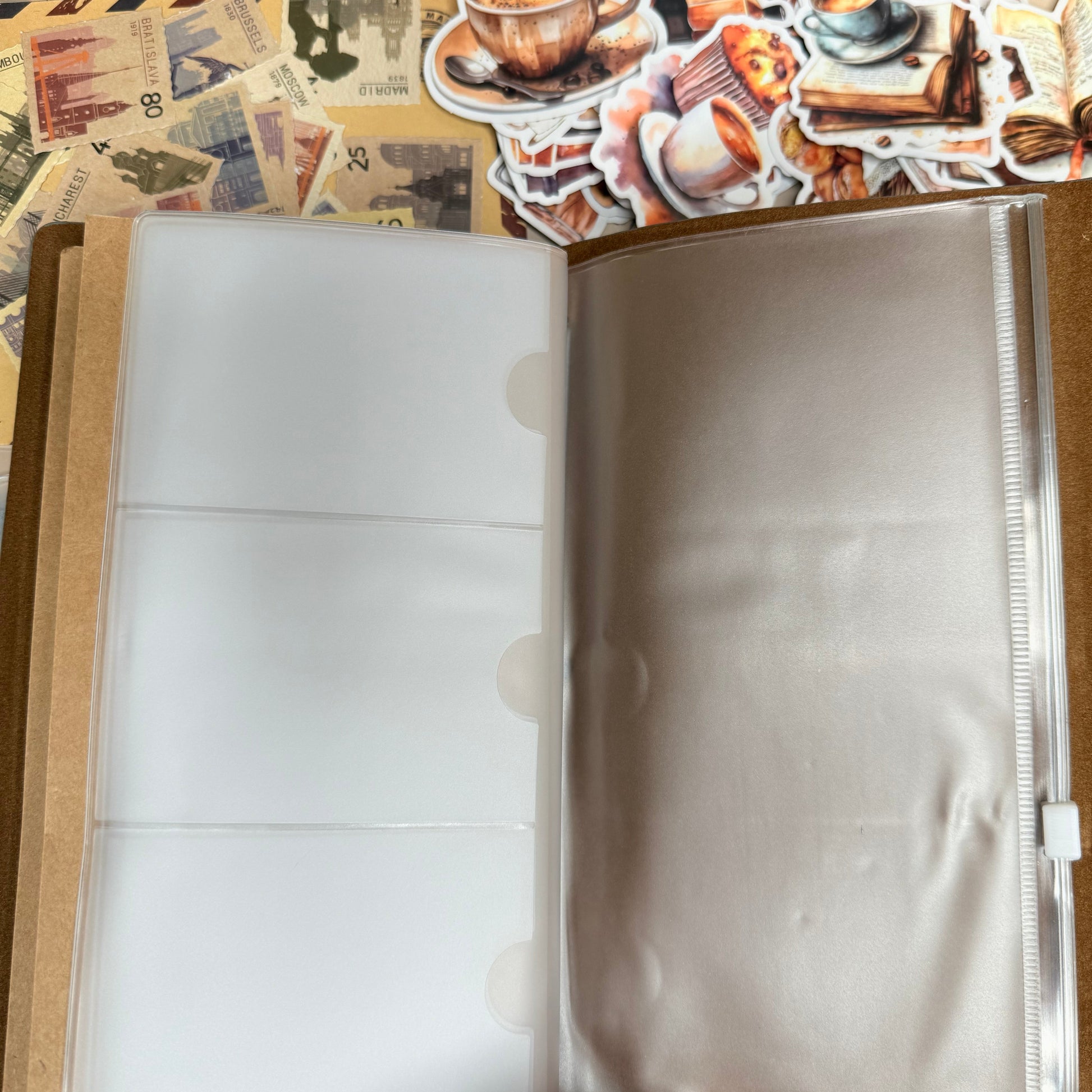 Open photo album with white pages and decorative stickers on the cover