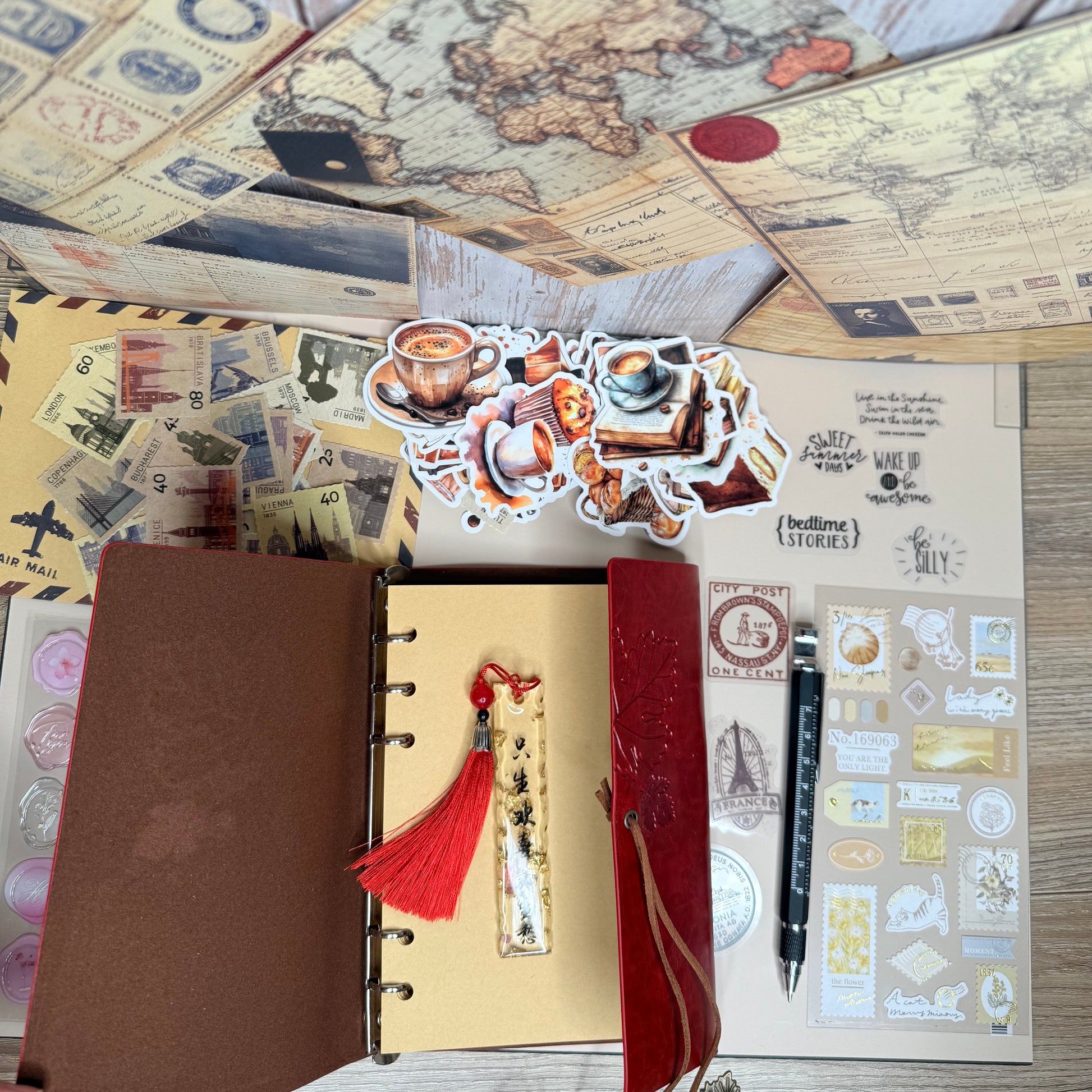 Decorative stationery items including a map, stickers, and a small notebook on a wooden surface.