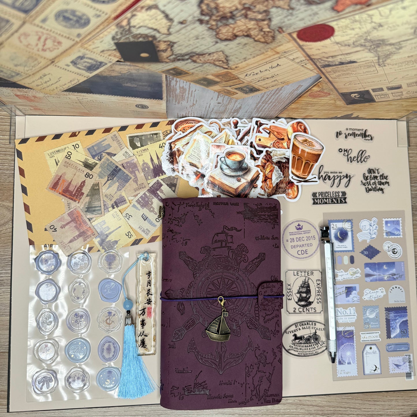 Stationery set with a purple notebook, stickers, and a map on a wooden surface