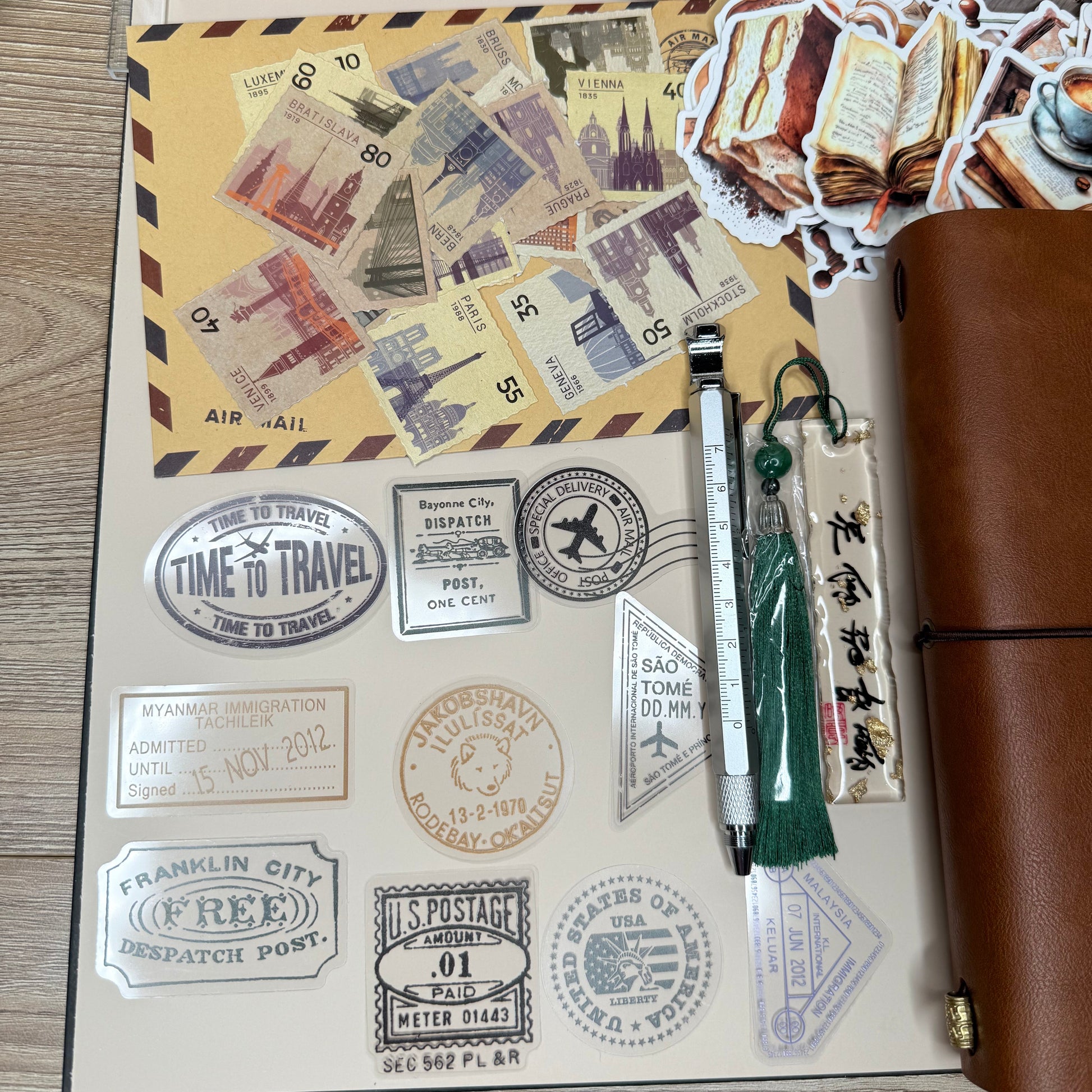 Stationery items including a pen, stickers, and travel-themed stamps on a wooden surface.