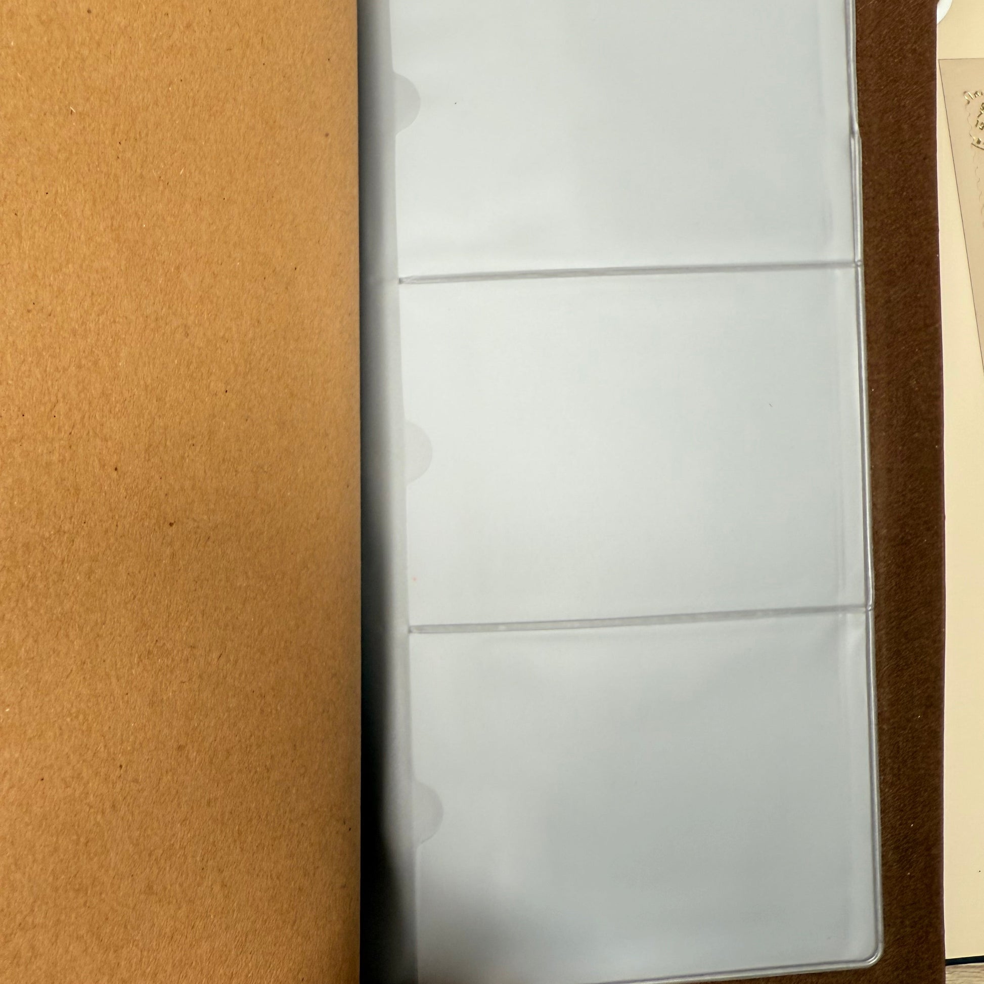 Empty photo album on a wooden surface with a hand holding it open.