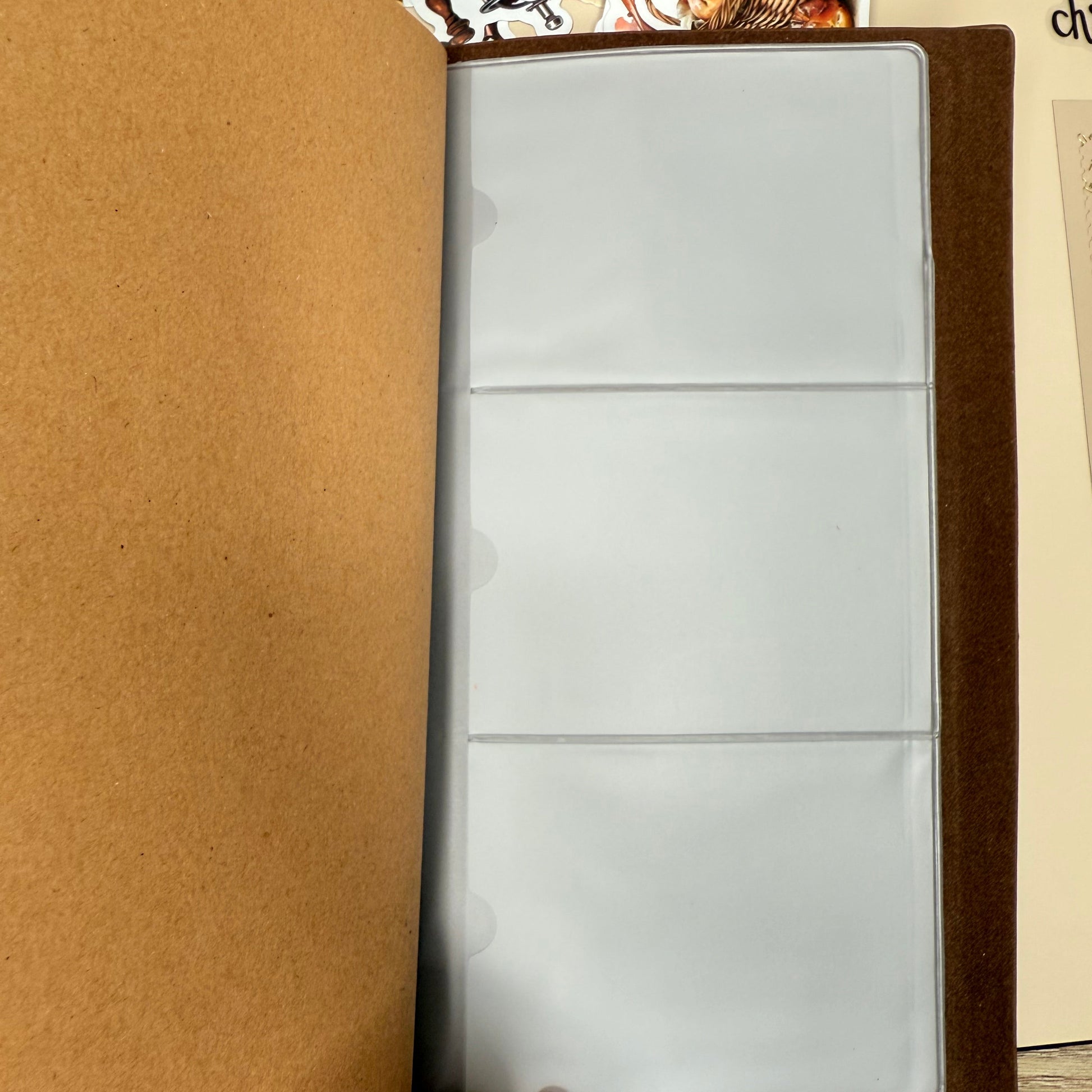 Brown leather-bound album with a hand holding it open on a wooden surface.