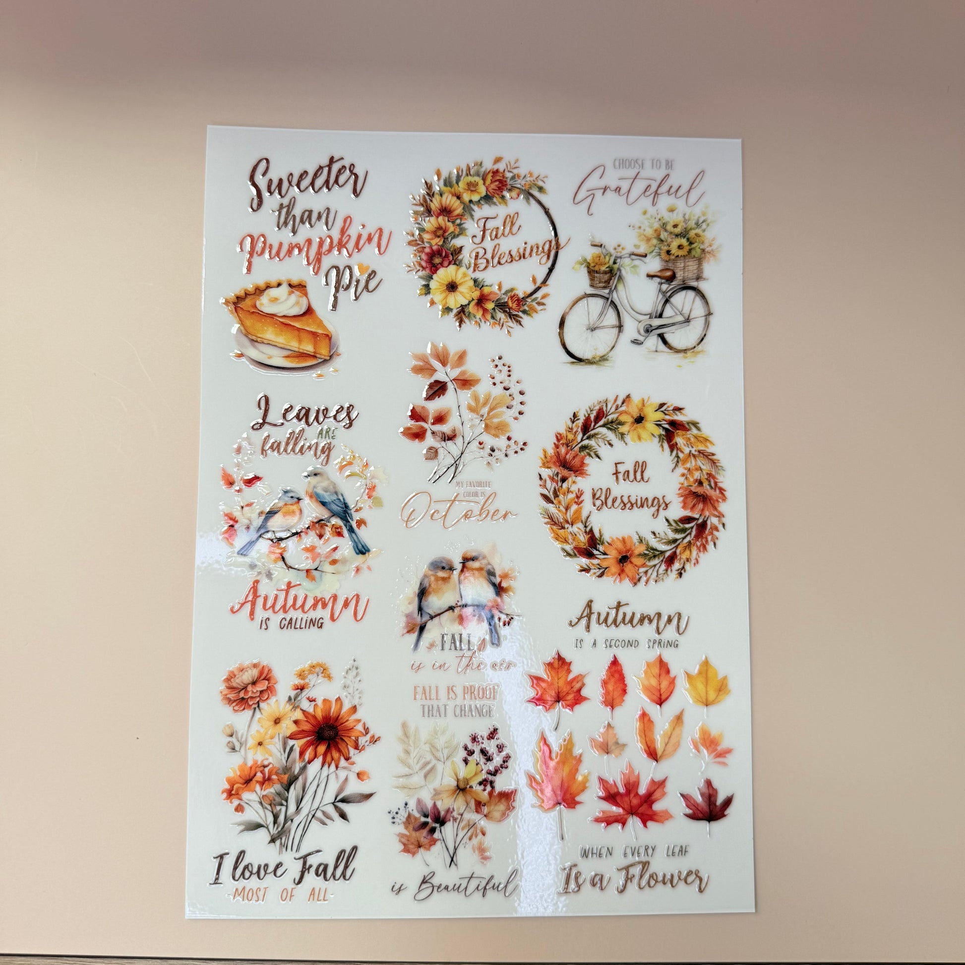Sheet of autumn-themed stickers with leaves, wreaths, and text on a beige background