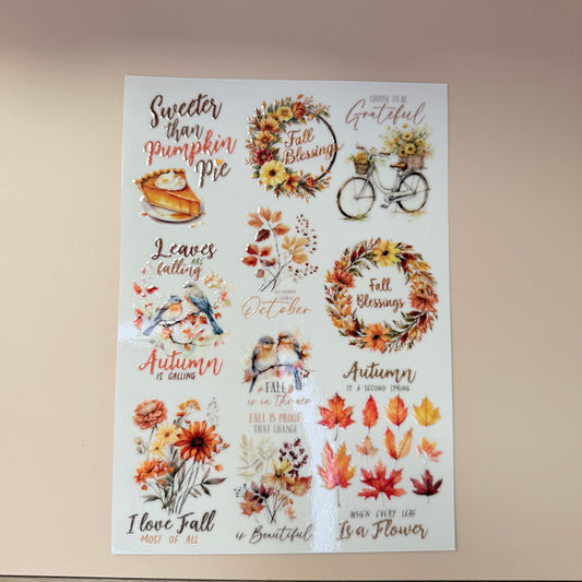 Sheet of autumn-themed stickers with leaves, wreaths, and text on a beige background