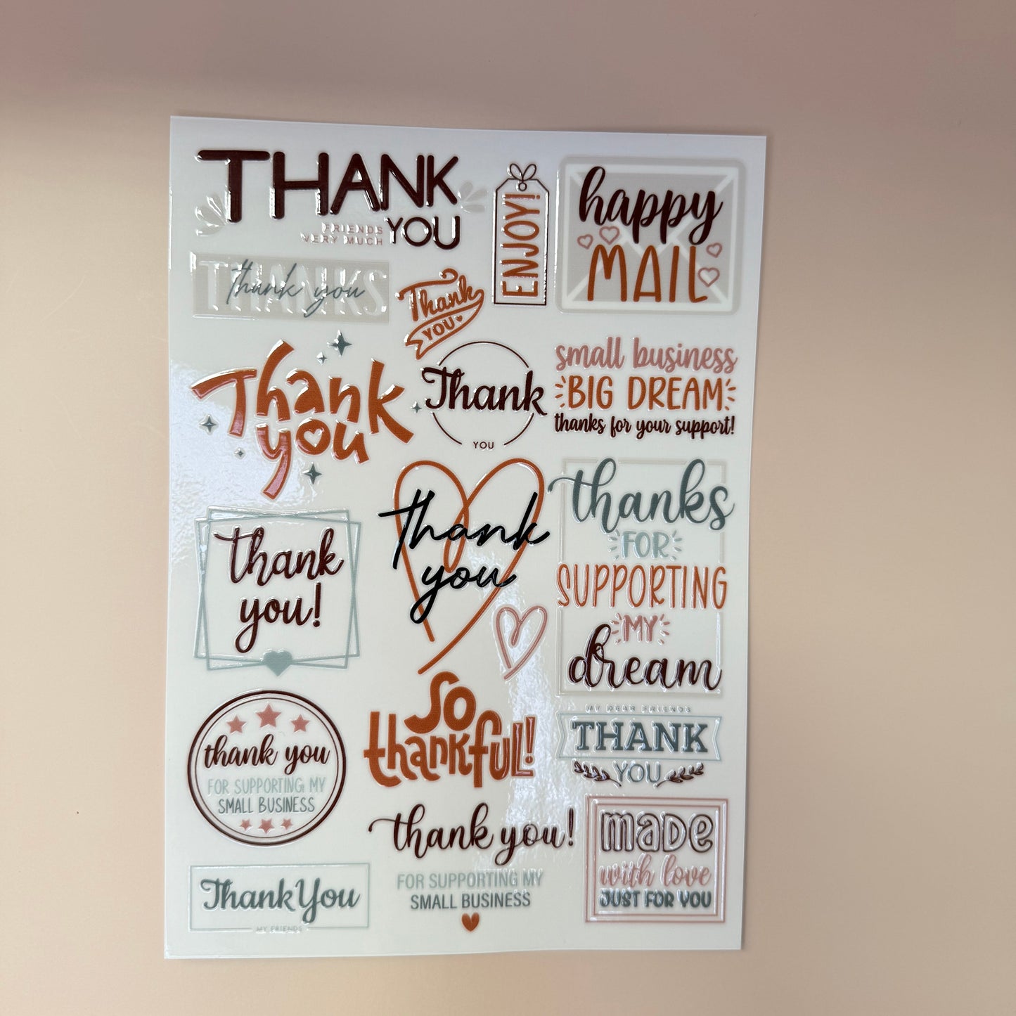 Sheet of decorative stamps with various 'thank you' phrases on a beige background.