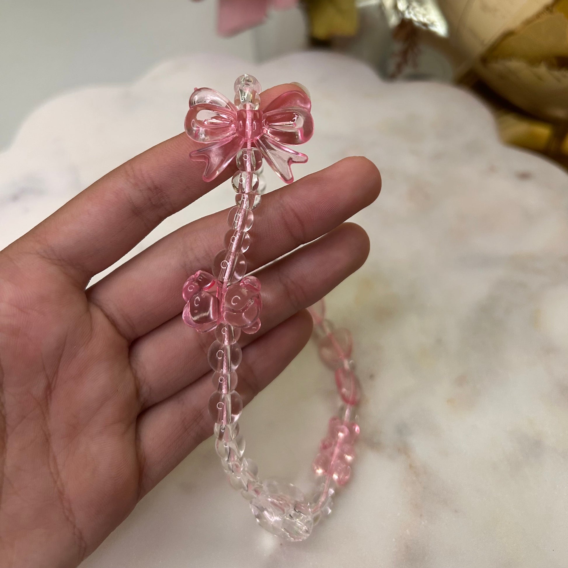Hand holding a pink beaded bracelet with a blurred background