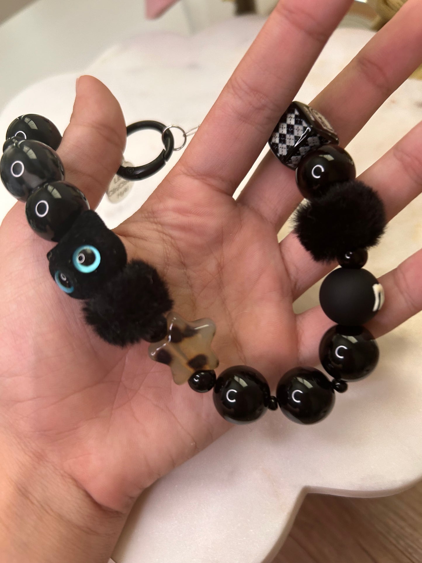 Hand holding a black beaded bracelet with decorative elements