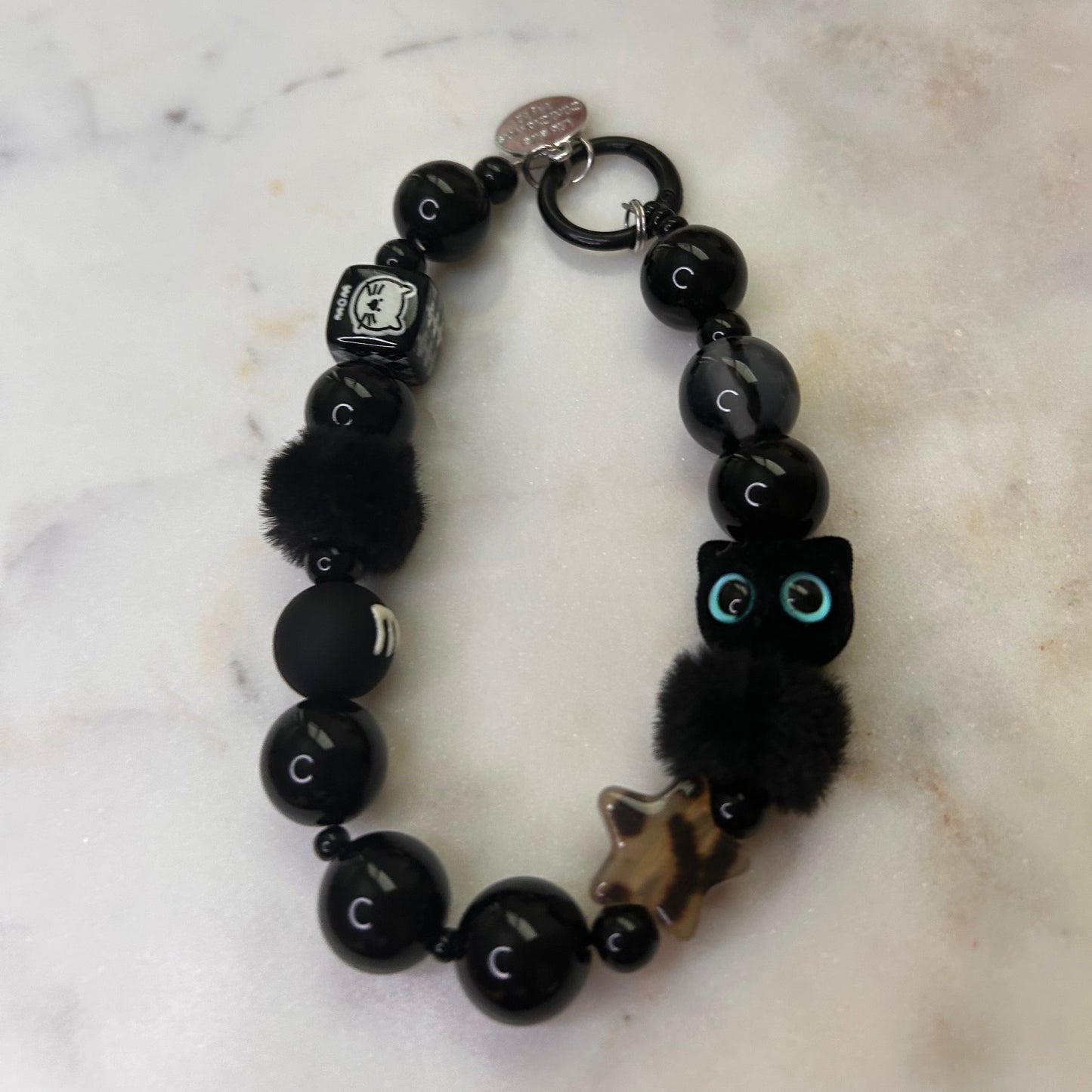 Black beaded bracelet with charms on a marble surface