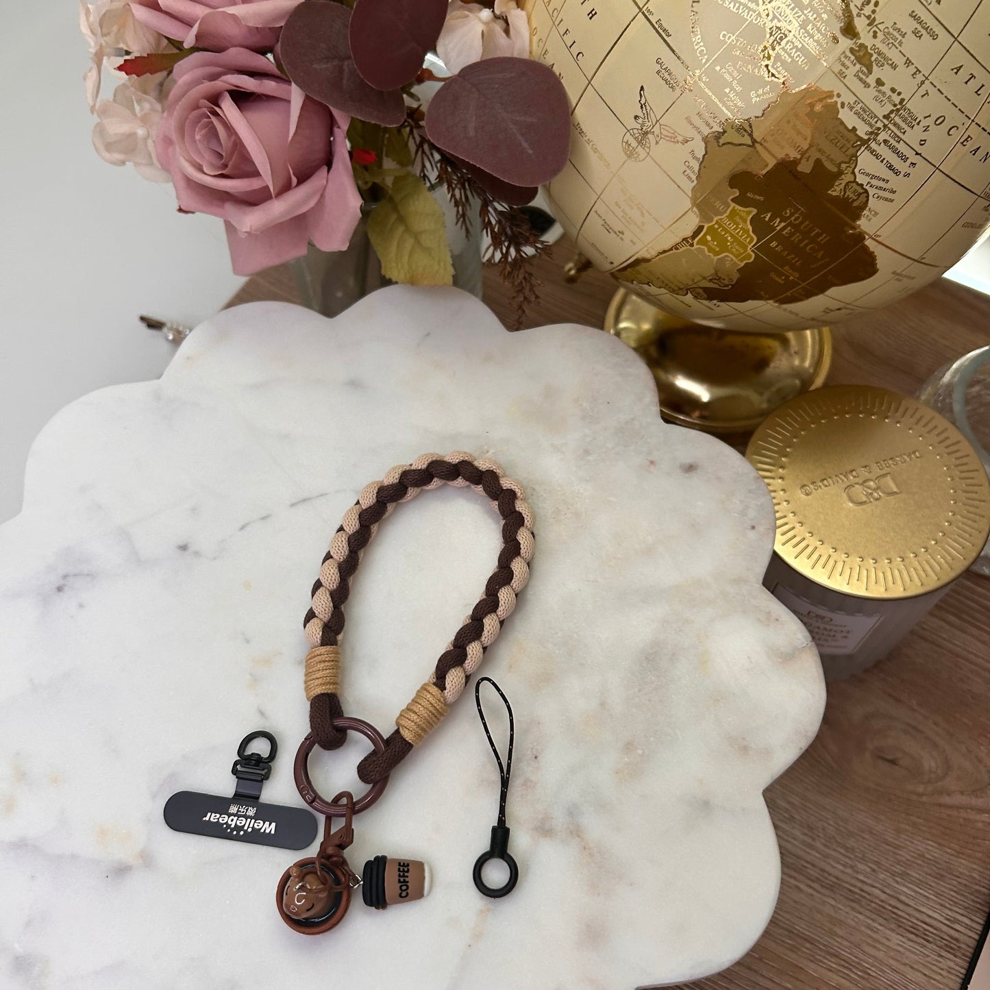Bracelet with keychain on a marble surface next to flowers and a globe