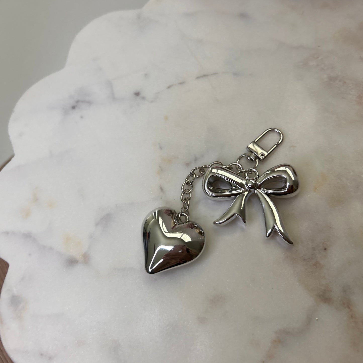 Silver angel and heart keychain on a marble surface