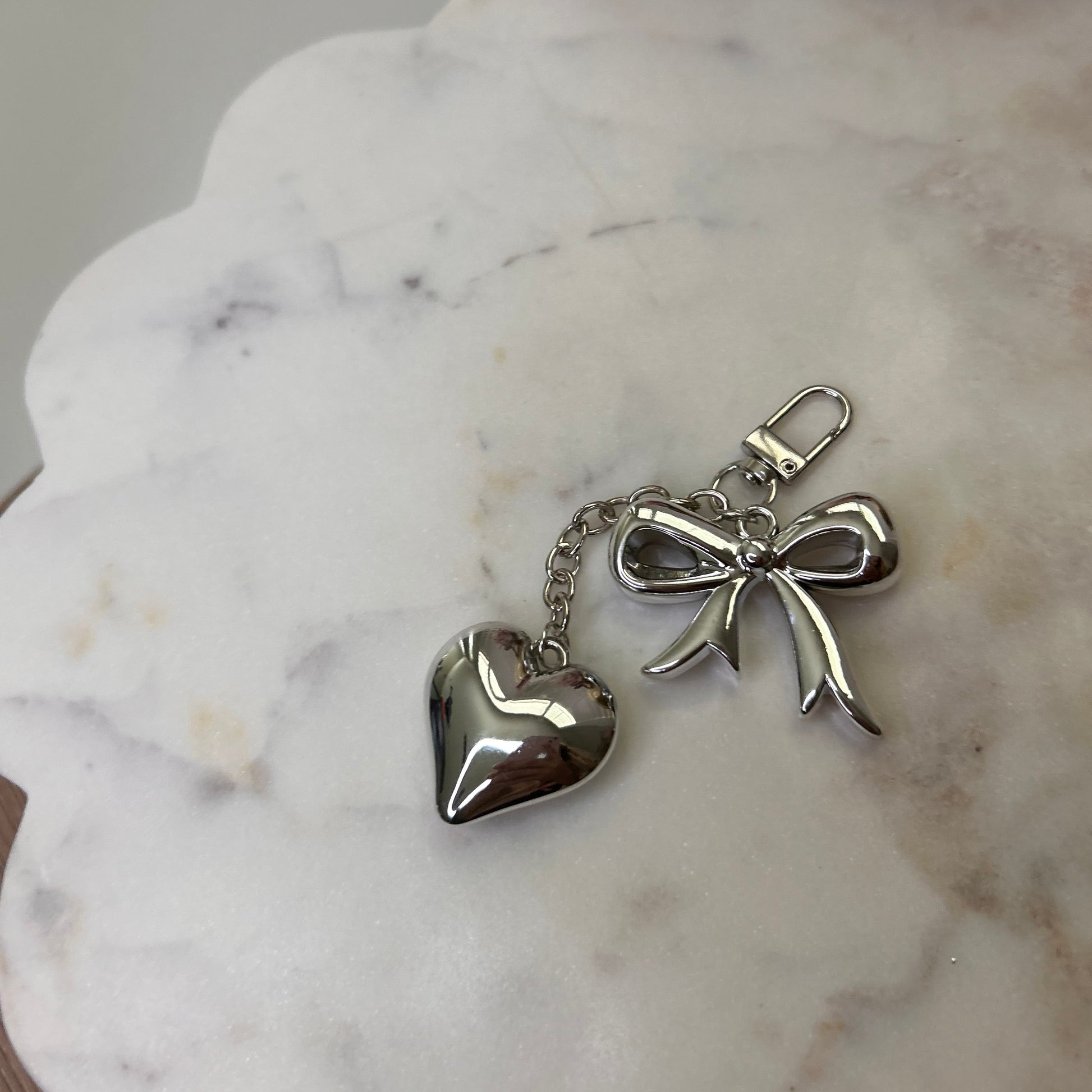 Silver angel and heart keychain on a marble surface