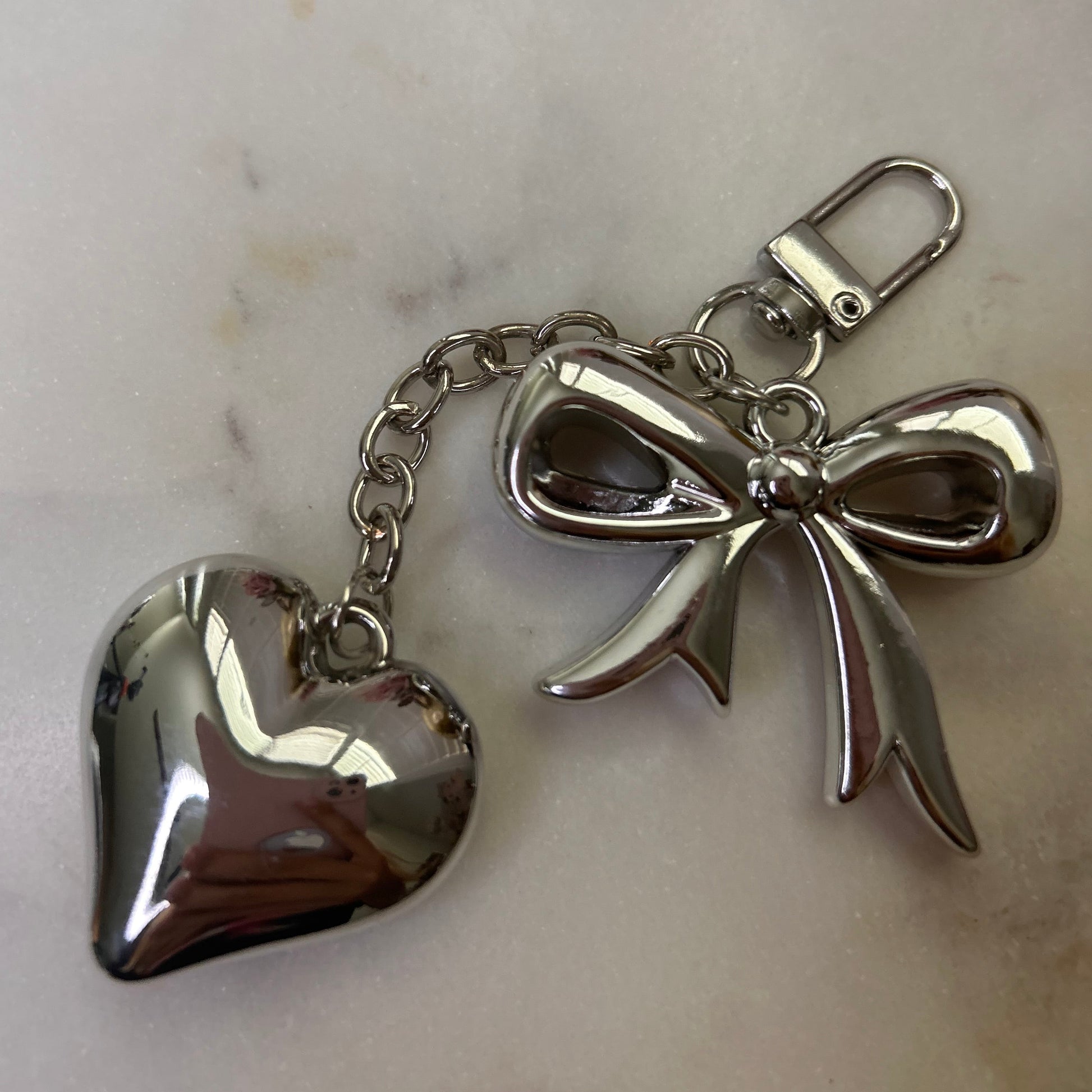 Silver angel and heart keychain on a marble surface