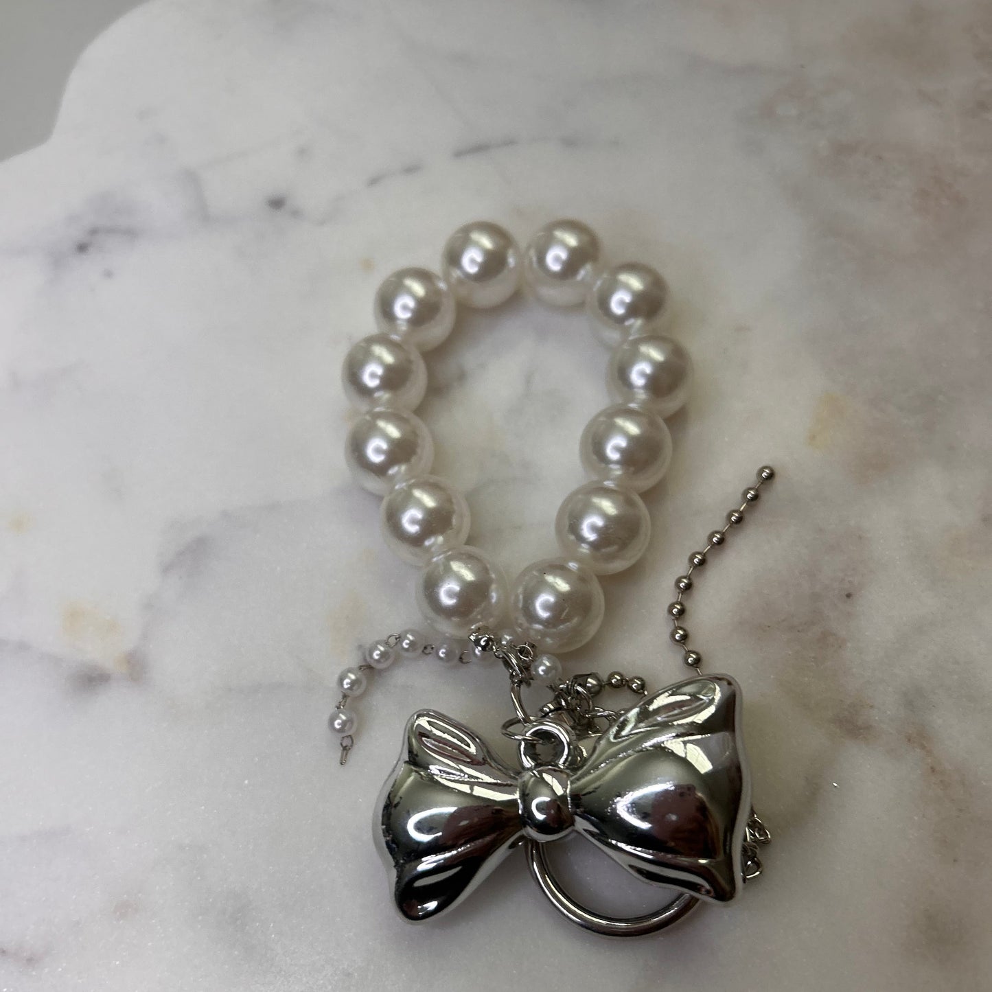 Pearl necklace with a silver pendant on a marble surface