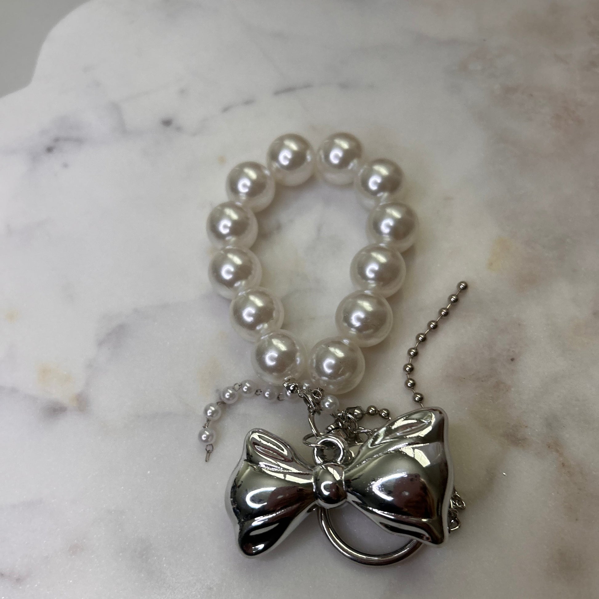 Pearl necklace with a silver pendant on a marble surface