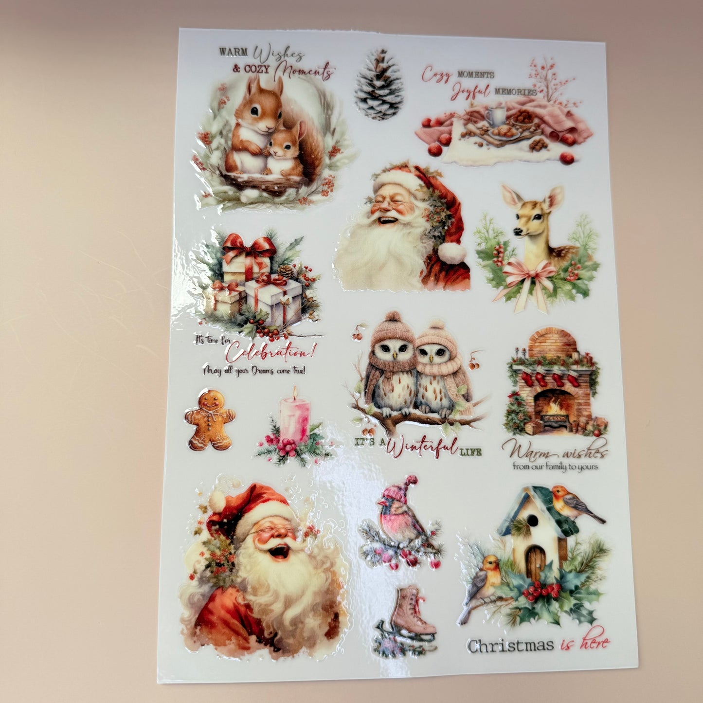 Sheet of Christmas-themed stickers featuring Santa Claus, reindeer, and winter elements on a beige background.